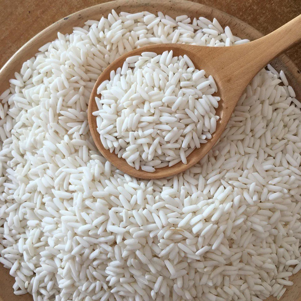White rice grains in a wooden bowl and spoon